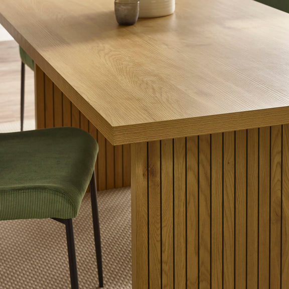 Wooden dining table with a green chair in a room setting