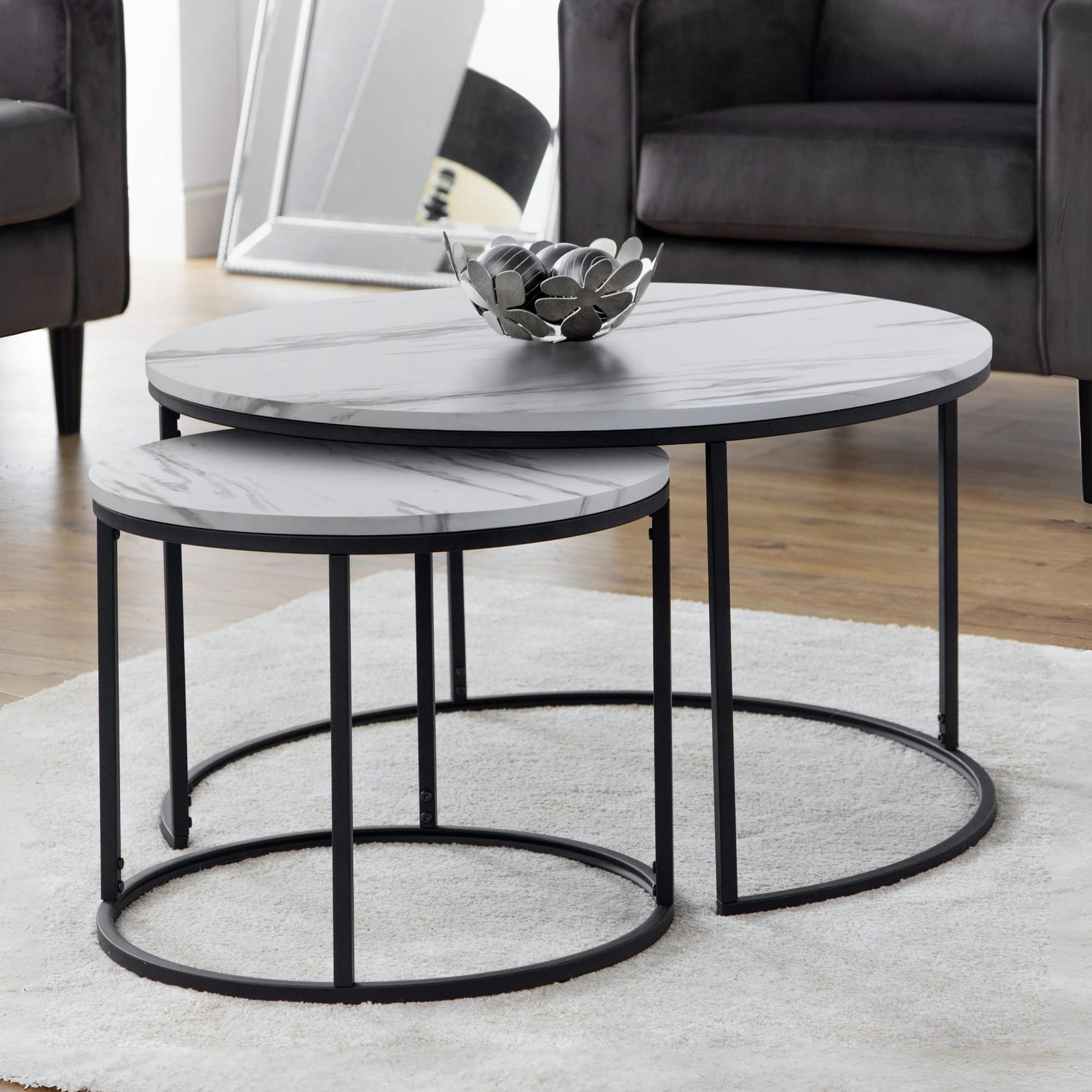 Set of two round marble coffee tables with black metal frames in a living room setting.