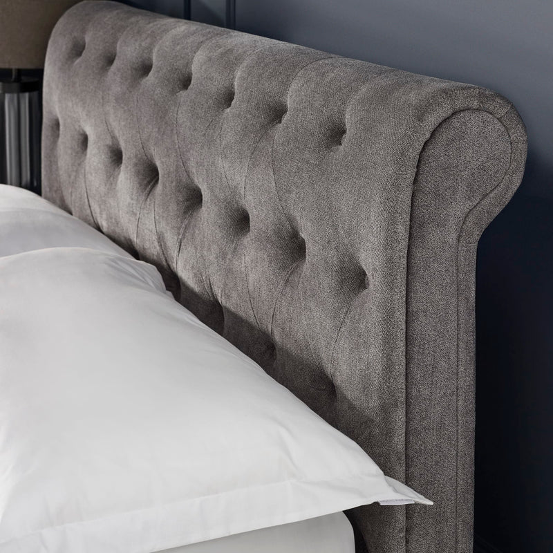 Gray tufted headboard with white pillows on a bed