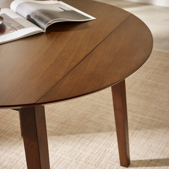 Wooden dining table with a magazine on top, set against a neutral background