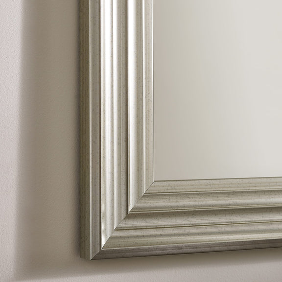 Close-up of a silver framed mirror on a neutral background