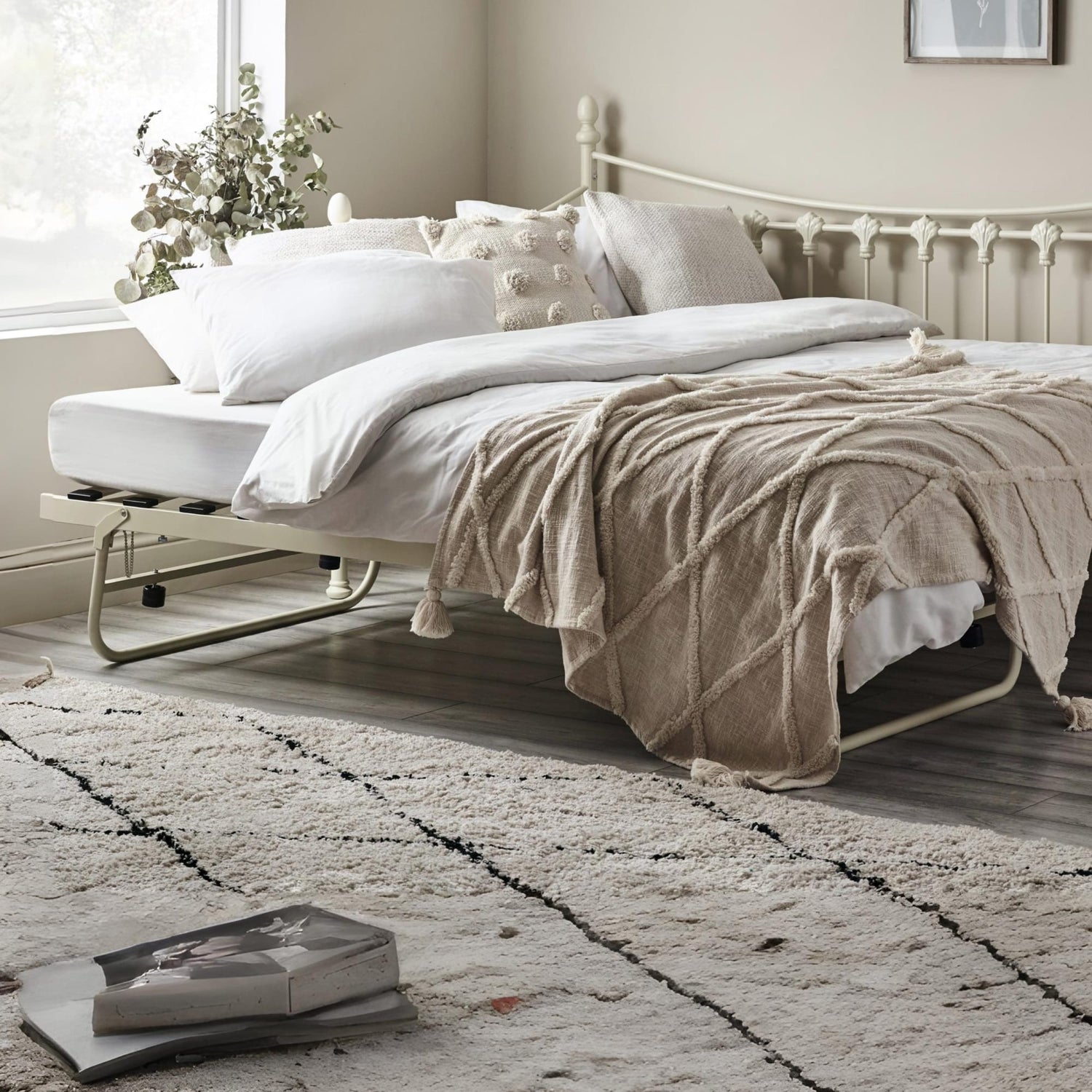 Bedroom with a bed, pillows, and a blanket on a wooden floor.
