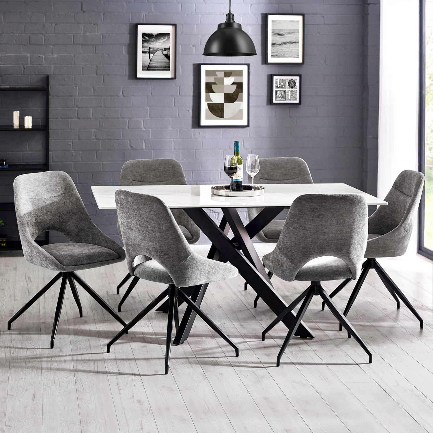 Dining room with a round table and gray chairs against a gray brick wall.