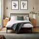 Neatly made bed with decorative pillows and a blanket in a bedroom setting.
