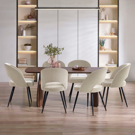 Dining room with a wooden table and white chairs, shelves in the background.