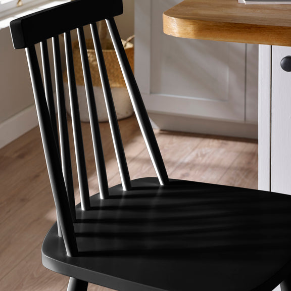 Black wooden chair in a kitchen setting with a wooden table.