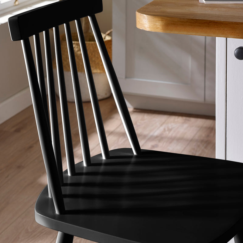 Black wooden chair in a kitchen setting with a wooden table.