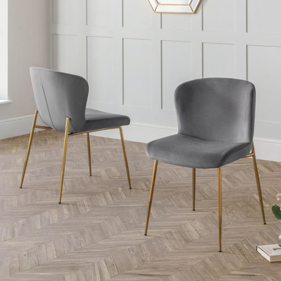 Two gray chairs with gold legs on a wooden floor.