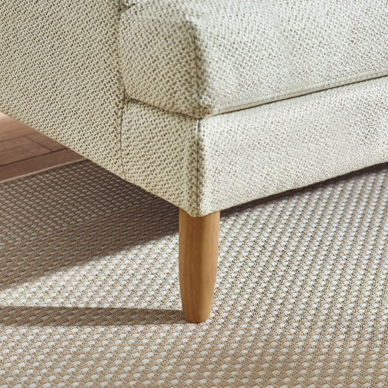 Close-up of a textured sofa corner with wooden leg on a patterned carpet