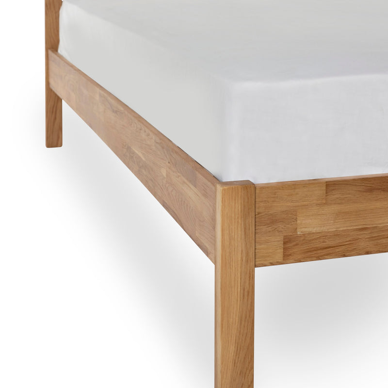 Wooden bed frame with white mattress on a white background