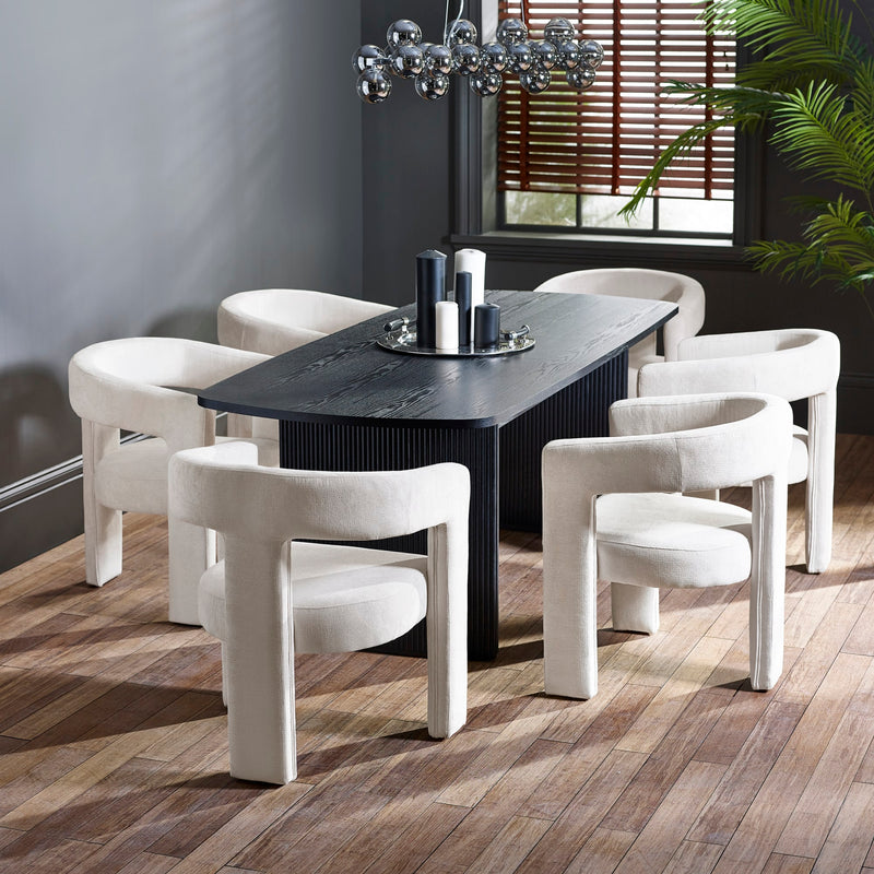 Dining room with a black rectangular table and white chairs on a wooden floor.