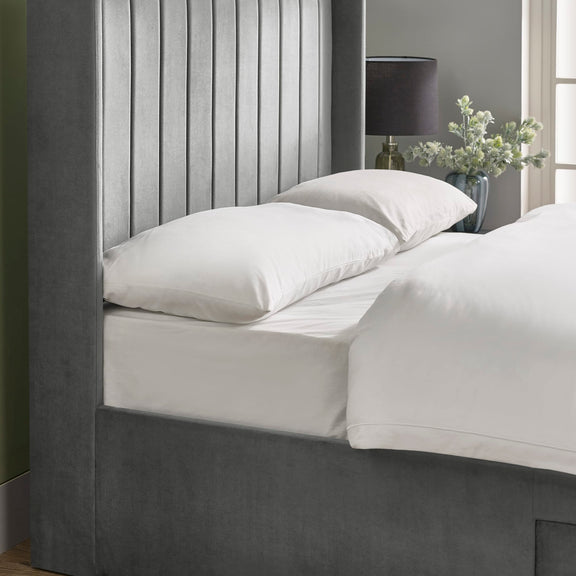Bed with white bedding and pillows in a bedroom setting.