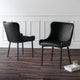 Two black chairs on a wooden floor with a white paneled wall in the background.