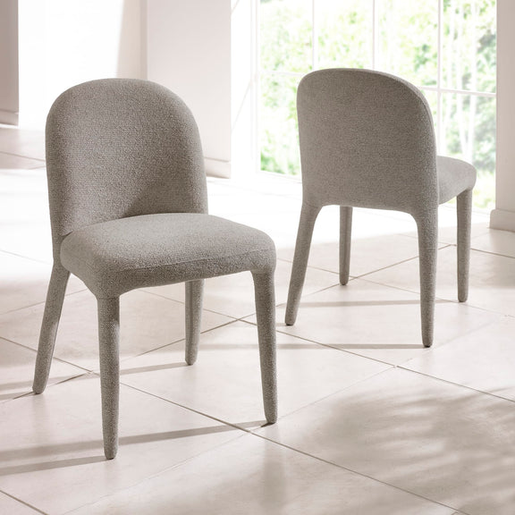 Two gray upholstered chairs on a tiled floor with a window in the background