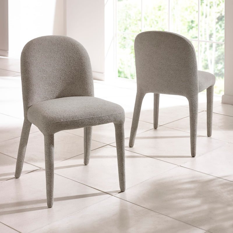 Two gray upholstered chairs on a tiled floor with a window in the background