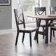 Dining table with black chairs in a room with large windows.