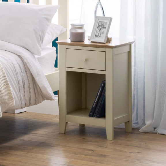 Beige nightstand with a wooden top next to a bed with white bedding.