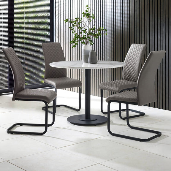 Round dining table with four gray chairs in a modern indoor setting.