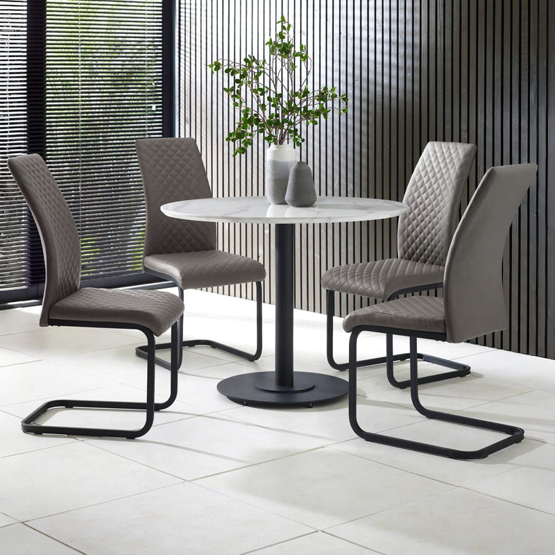 Round dining table with four gray chairs in a modern indoor setting.