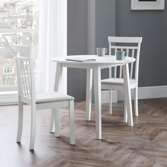 White dining table with chairs in a room with a gray wall and window.