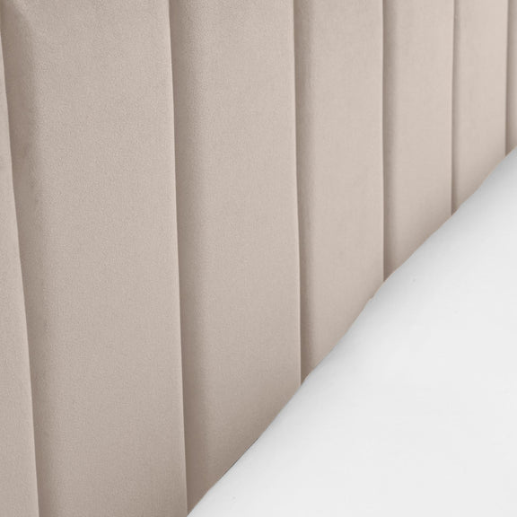 Close-up of beige pleated curtains with a white surface.