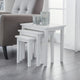 Set of white nesting tables with glass holders in a living room setting.