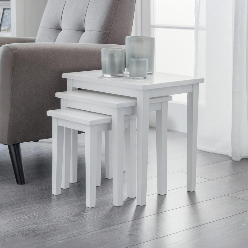 Set of white nesting tables with glass holders in a living room setting.
