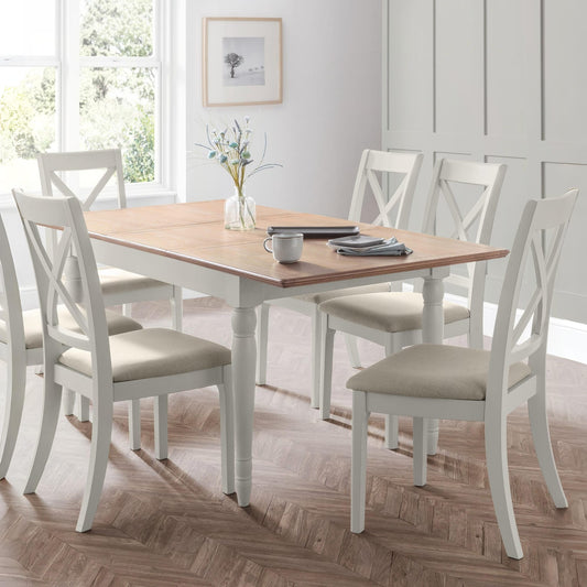 Dining room with a wooden table and white chairs on a wooden floor.