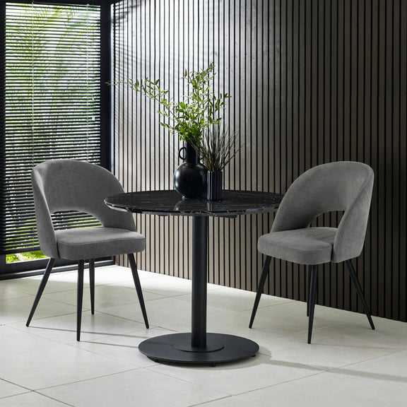 Modern black round table with two gray chairs in a room with striped walls.