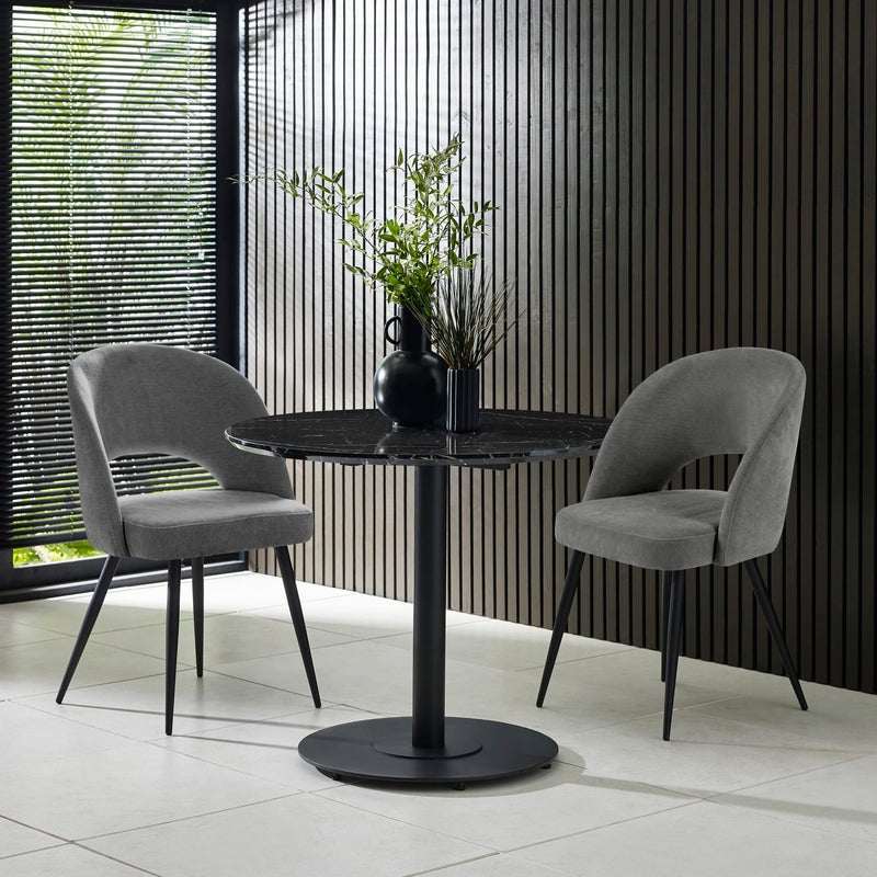 Modern black round table with two gray chairs in a room with striped walls.
