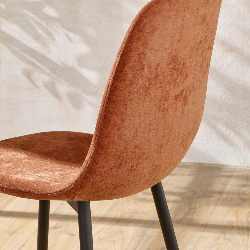 Brown upholstered chair with black legs on a light wooden floor.