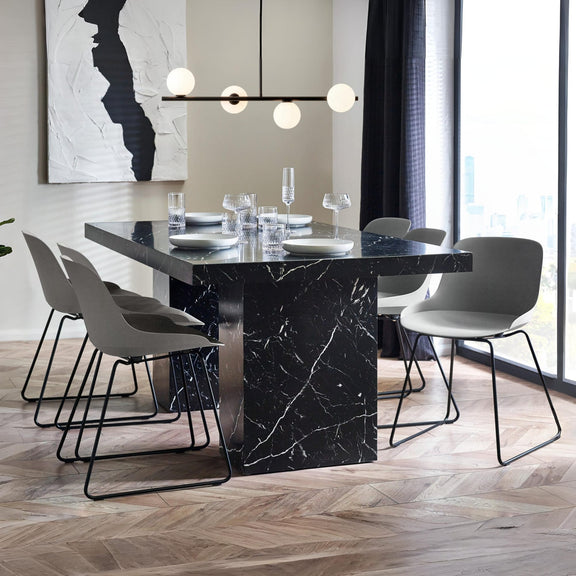 Modern dining room with a black marble table and gray chairs.