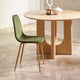 Green chair in front of a wooden dining table on a wooden floor.