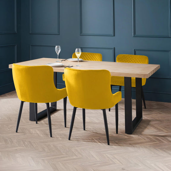 Dining table with yellow chairs against a blue paneled wall.