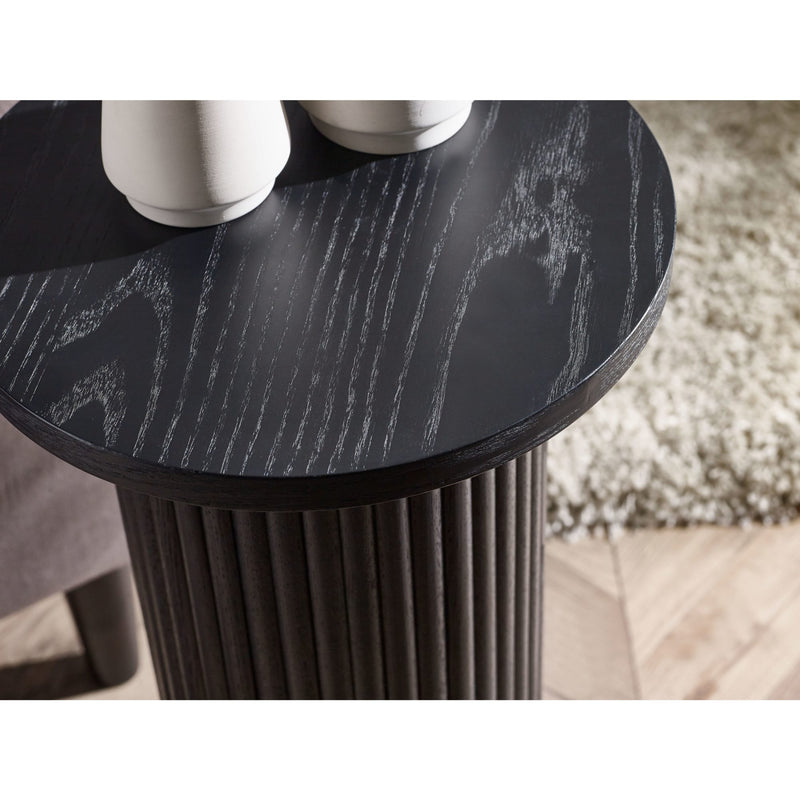 Round black marble table with cylindrical base on a light wood floor.