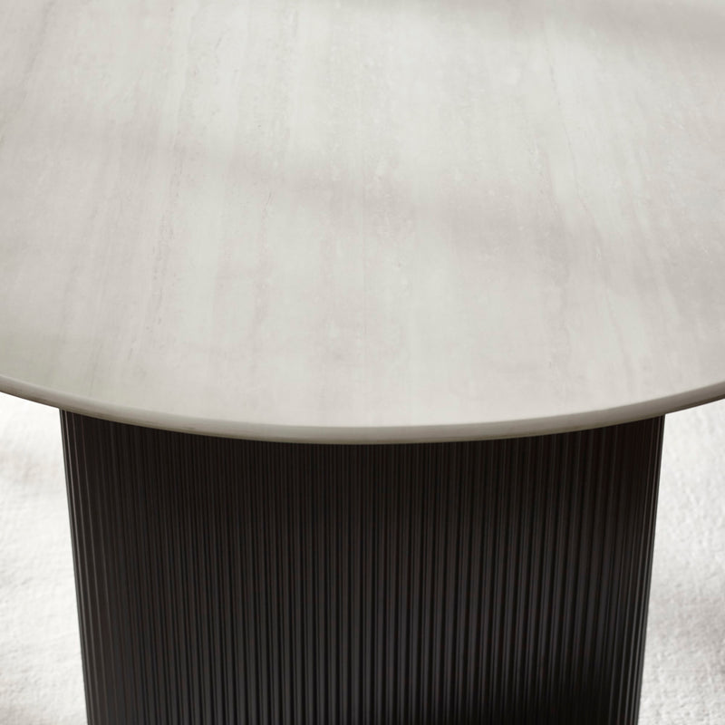 Round table with a light-colored top and dark ribbed base on a neutral background
