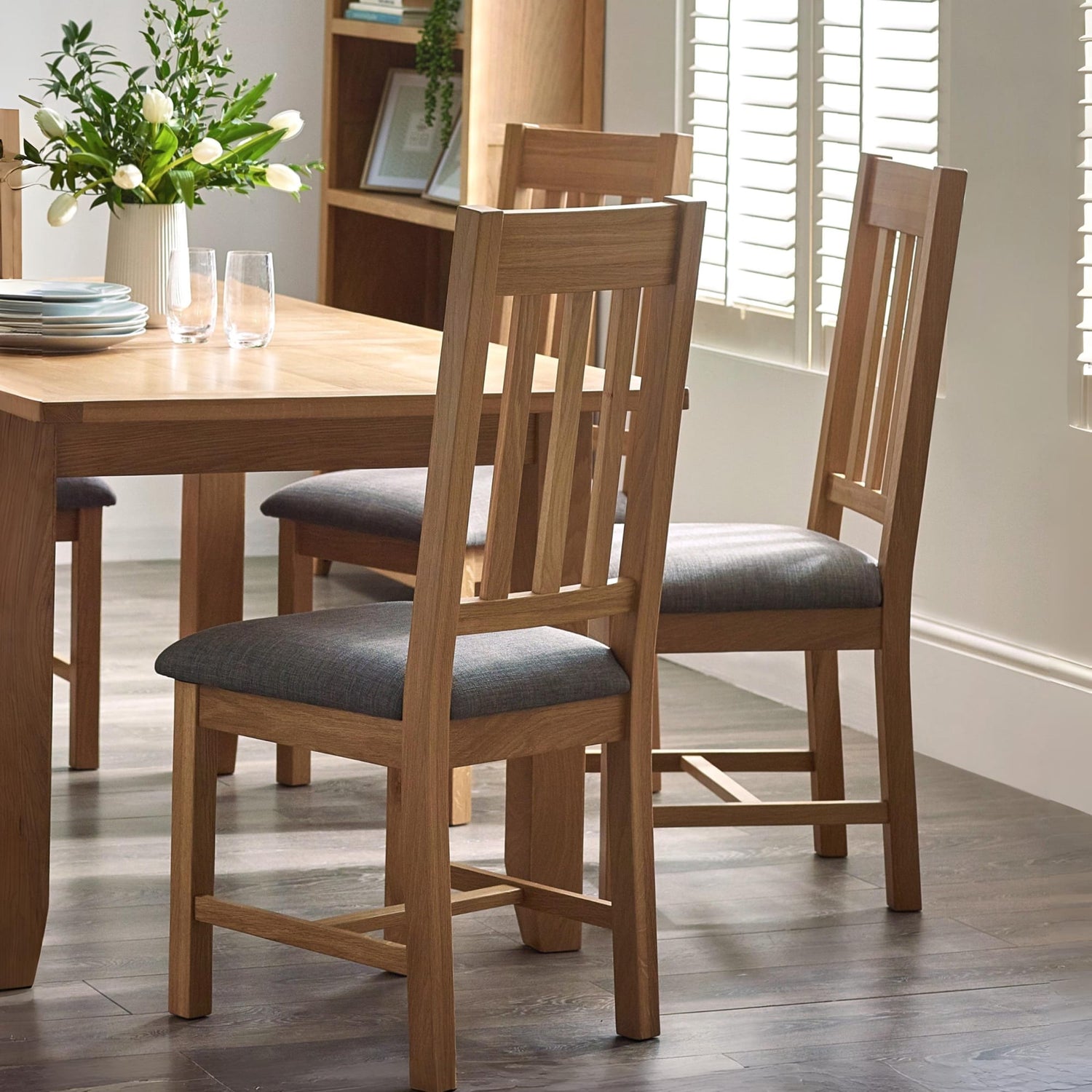 Dining room with wooden table and chairs, and a vase of flowers on the table.