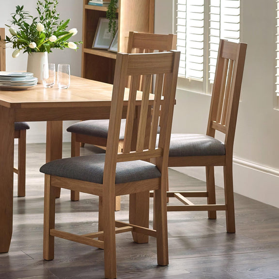 Dining room with wooden table and chairs, and a vase of flowers on the table.
