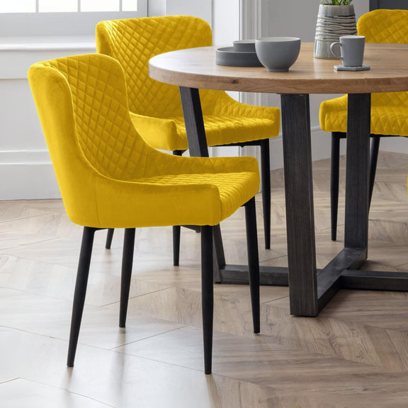 Yellow chairs around a wooden dining table with gray bowls and mugs.