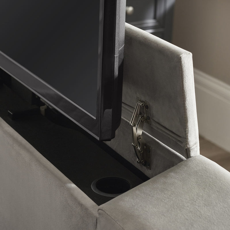 Gray upholstered chair with a television mounted on a wall-mounted shelf.