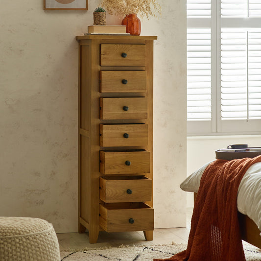 Tall wooden dresser with multiple drawers in a bedroom setting.