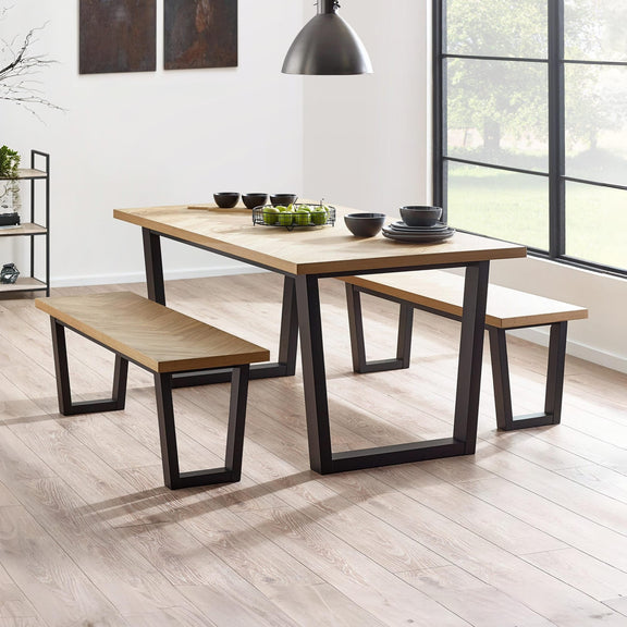 Dining table with benches in a modern room with large windows.