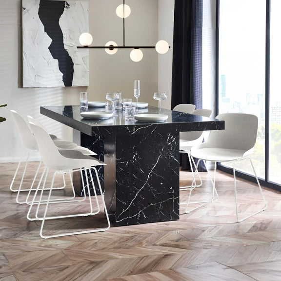 Modern dining room with black marble table and white chairs.