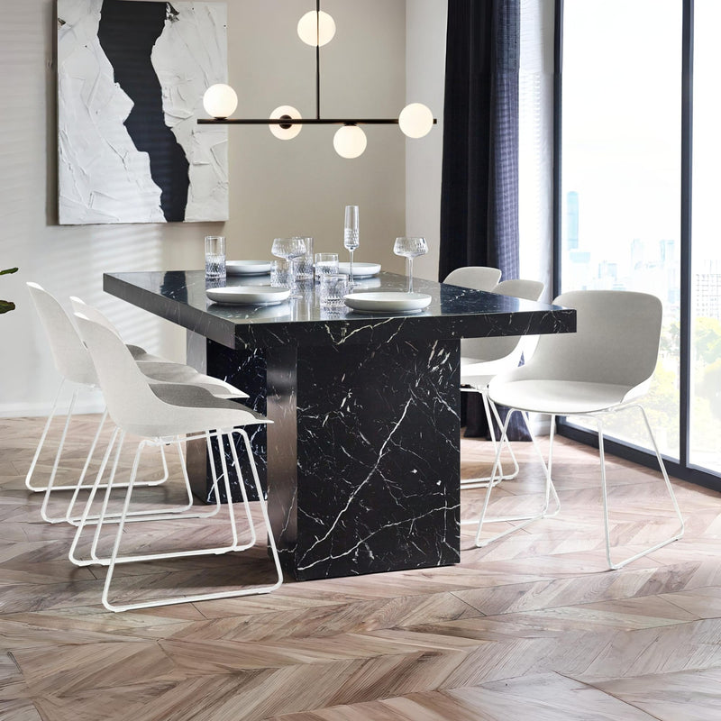 Modern dining room with black marble table and white chairs.