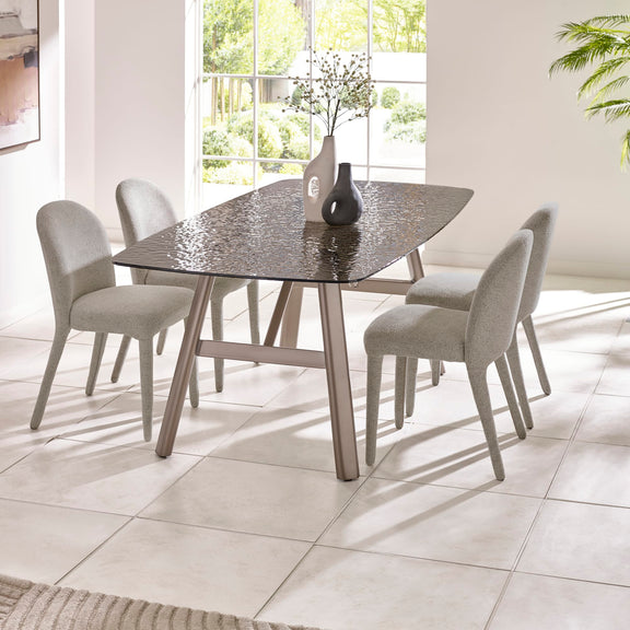 Dining table with four chairs in a bright room with large windows.