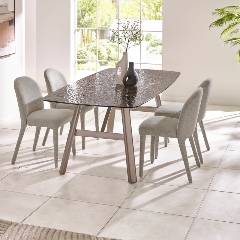 Dining table with four chairs in a bright room with large windows.