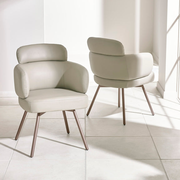 Two modern beige chairs with wooden legs on a light tiled floor.
