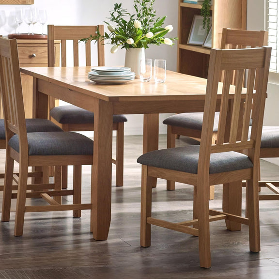 Wooden dining table with chairs and a vase of flowers in a room.