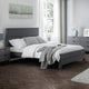 Modern bedroom with gray bed frame, white bedding, and decorative elements.