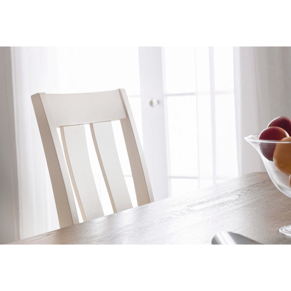 White chair and table with a bowl of fruit in a bright room